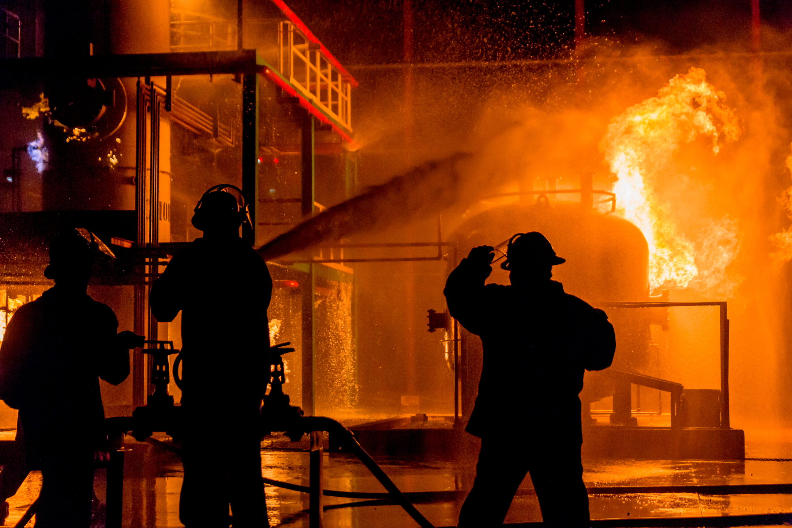 Firemen using water from hose for fire fighting at firefight tra